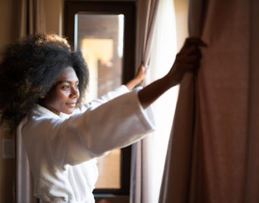 Woman pulling curtains in hotel room