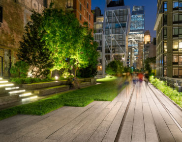 The High Line promenade illuminated at twilight surrounded by modern and older buildings in Chelsea. The aerial greenway is also known as Highline or High Line Park. Manhattan, New York CIty